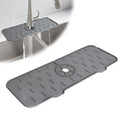 CrystalWash silicone faucet mat in dark grey, shown protecting a kitchen sink countertop from water splashes.