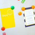 Close-up of vibrant 2cm plastic magnetic pins on a white board surface.