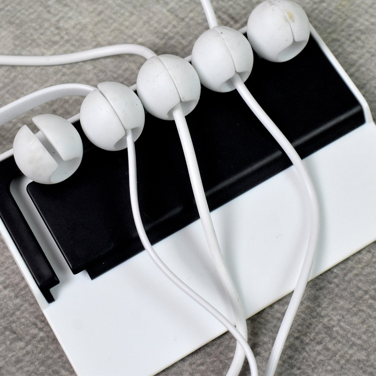 Adhesive cable holder attached to a wall for workspace organization