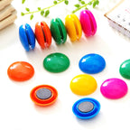 Circular board magnets in assorted colors displayed on a surface.