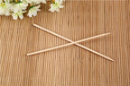 A hand holding a bamboo BBQ skewer with various ingredients for grilling.